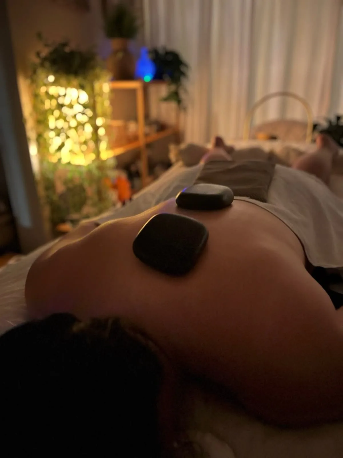 Massagem com pedras quentes em sala à meia-luz
